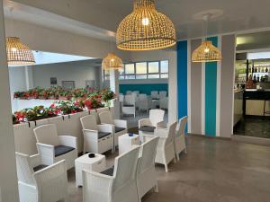 a restaurant with white chairs and tables and flowers at Hotel Amalfi & Dépendance in Lignano Sabbiadoro