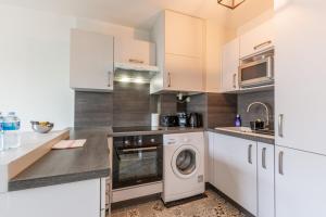 a kitchen with white cabinets and a washer and dryer at Sunshine by Plaza - Proche Disneyland Paris in Montévrain