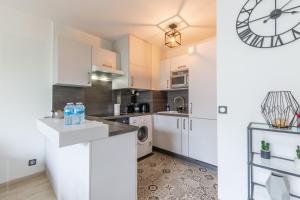a kitchen with white cabinets and a clock on the wall at Sunshine by Plaza - Proche Disneyland Paris in Montévrain