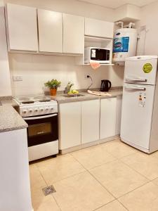 Una cocina con gabinetes blancos y un refrigerador blanco. en COMPLEJO ZAPALA, en Villa Hipódromo