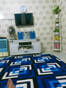 a living room with a tv and a blue and white rug at Shifana homestay syariah in Yogyakarta