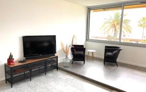 uma sala de estar com uma televisão de ecrã plano e cadeiras em Plage Landsberg Appartement 2 pièces en bord de mer em Saint-Laurent-du-Var