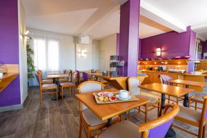 a restaurant with wooden tables and chairs and purple walls at Hotel Aguado in Dieppe