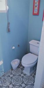 a bathroom with a white toilet and a blue wall at COZY NEST in Guayama