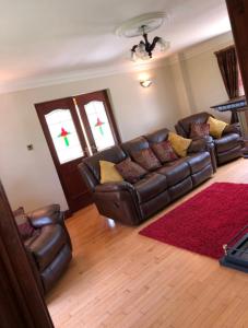 a living room with a leather couch and a red rug at Corraglass House - close proximity to Cuilcagh in Letterbreen