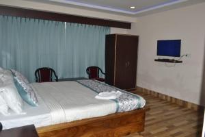 1 dormitorio con 1 cama y TV de pantalla plana en Golden Oren Hotels and Spa, en Darjeeling