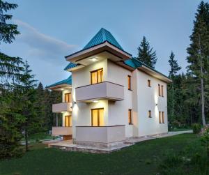 una grande casa bianca con tetto verde di Apartmani Bijelic a Žabljak
