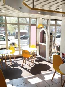 a cafeteria with tables and chairs and a window at EGG HOTEL - HOTEL LES GENS DE MER Dieppe in Dieppe