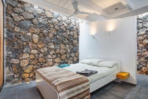 een slaapkamer met een bed met een stenen muur bij La Bodeguita House in Haría