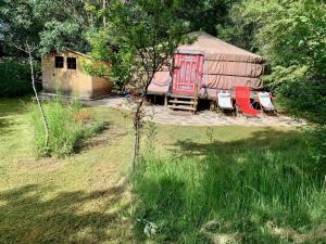 a yurt with chairs and a house in the grass at La Yurta de Gaia in San Lorenzo de El Escorial