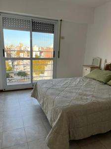een slaapkamer met een bed en een groot raam bij Hermoso departamento con parrillero. Zona Centro in Rosario