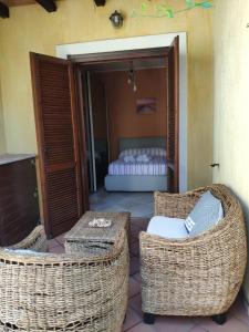 a patio with two wicker chairs and a bed at Il Borgo Del Sole in Villasimius