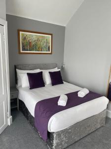 a bedroom with a large bed with purple and white pillows at Elmbank Stay - Drymen in Drymen