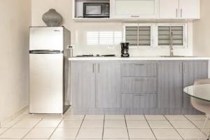a white kitchen with a refrigerator and a sink at Latitude Adjustment in San Juan