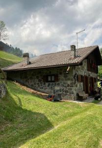 a stone house on a hill with a green field at Baita Palue in Torcegno