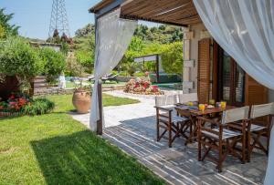 een patio met een tafel en stoelen in een tuin bij Maratho Villa, nature wellness experience, By ThinkVilla in Xiron Chorion