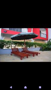 two benches with an umbrella in front of a building at Shanzu Beach apartment with stunning Ocean view in Mwakirunge