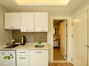 a kitchen with white cabinets and a sink at Sigacik Marina Apart Hotel in Siğacık