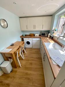 cocina con armarios blancos y mesa de madera en A secluded self contained Country Suite with a view - parking, easy access to Bath, en Corsham