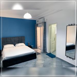um quarto azul com uma cama e um espelho em Nalabba em Dakar