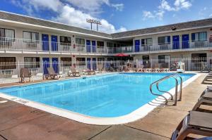 una piscina frente a un hotel con mesas y sillas en Motel 6-Slidell, LA - New Orleans, en Slidell