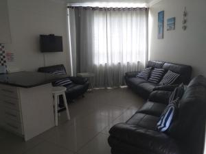 a living room with a black leather couch and chairs at Afsaal Holiday Flats in Amanzimtoti