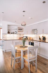 a kitchen with white cabinets and a table and chairs at Frances' Sketch Pad with Hot Tub in Fort William