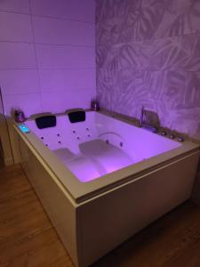a purple bathroom with a tub with a purple lighting at Gite Romantique avec Espace Balnéo et Ciel Etoilé "La Maison du Bonheur Saint Germer de Fly" Nuit Romantique Oise, Picardie, Normandie in Saint-Germer-de-Fly