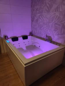 d'une salle de bains pourpre pourvue d'une baignoire avec un éclairage violet. dans l'établissement Gite Romantique avec Espace Balnéo et Ciel Etoilé "La Maison du Bonheur Saint Germer de Fly" Nuit Romantique Oise, Picardie, Normandie, à Saint-Germer-de-Fly