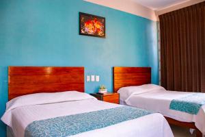 - une chambre avec 2 lits et un mur bleu dans l'établissement Acapulco Amor, à Acapulco