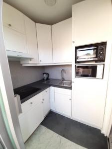 a kitchen with white cabinets and a sink and a microwave at Residence Albert Premier in Menton