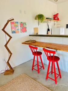 a kitchen with a wooden table and two red stools at Villa Yvytu - Praia do Preá in Prea