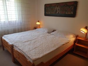 1 cama en un dormitorio con 2 lámparas en las mesas en Bot Sundroina (329 Pe) Whg. 2.3, en Lenzerheide