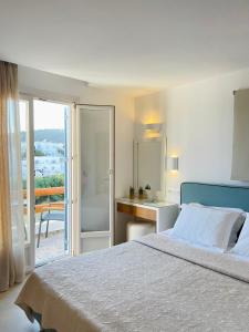a bedroom with a bed and a desk and a balcony at Esperides in Platis Yialos Mykonos