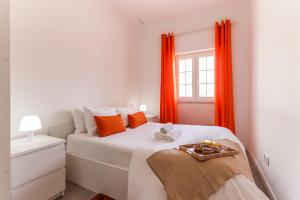 1 dormitorio con cama blanca y cortinas de color naranja en Downtown Lisbon Palma Suites by Homing, en Lisboa