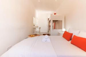 una camera da letto con un grande letto bianco con cuscini arancioni di Downtown Lisbon Palma Suites by Hosty a Lisbona