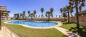 a swimming pool in a yard with palm trees at Apartamento Residencial Mirador Playa Serena in Roquetas de Mar