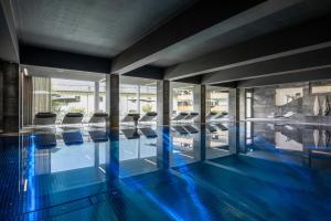 a swimming pool with blue floors and glass walls at Sporthotel Silvretta Montafon in Gaschurn