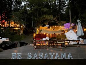 eine Gruppe von Stühlen und Sonnenschirmen auf einer Terrasse in der Nacht in der Unterkunft MUSIC FOREST Villa&Camp in Sasayama