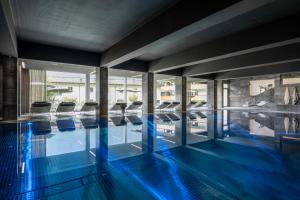 a swimming pool with blue floors and glass walls at Sporthotel Chalet in Gaschurn