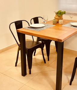 a wooden table with two chairs and two glasses of wine at COMPLEJO ZAPALA in Villa Hipódromo