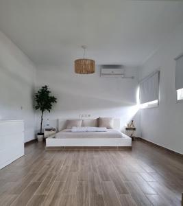 a white bedroom with a bed and a wooden floor at La Maison de Kouadio in Abidjan