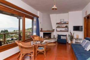 a living room with a table and chairs and a balcony at Seaside House with view over Pagasitikos in Afissos