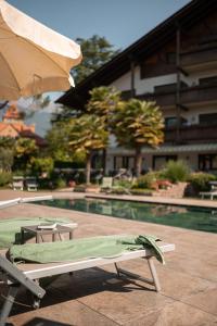 uma piscina com uma chaise longue e um guarda-sol em Hotel Salgart em Merano