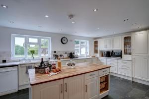 uma cozinha com armários brancos e um balcão de madeira em Norfolk Holiday Cottage 4-Bed Luxury Dog friendly em Heacham