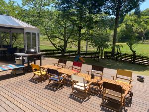 een houten terras met stoelen en een tafel en een grill bij MUSIC FOREST Villa&Camp in Sasayama