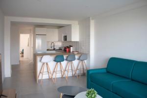 a living room with a blue couch and a kitchen at Appartement rénové, terrasse vue mer in Cagnes-sur-Mer