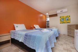 1 dormitorio con 2 camas y pared de color naranja en Porto Seguro Flat, en Pecém