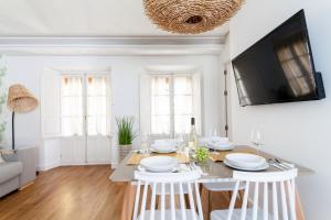 a white living room with a dining room table with white chairs at Green-Apartments San Francisco in Seville