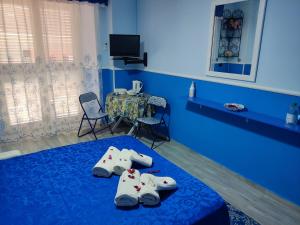 a blue room with a bed with pairs of slippers at Da zio Michele in Scilla
